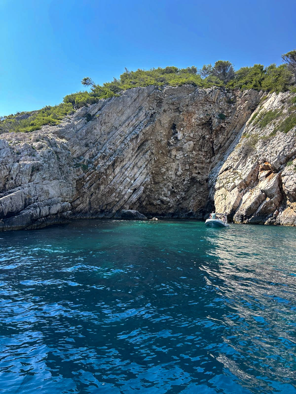 Hidden cove with towering cliffs and a boat anchored in emerald water