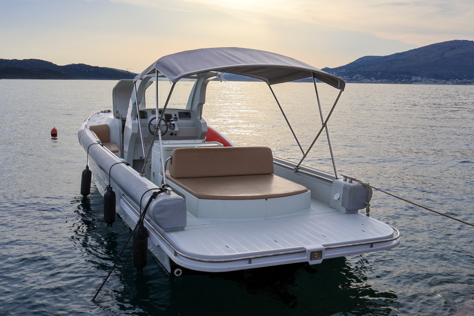 The boat moored at golden hour with its bimini top and sun bed
